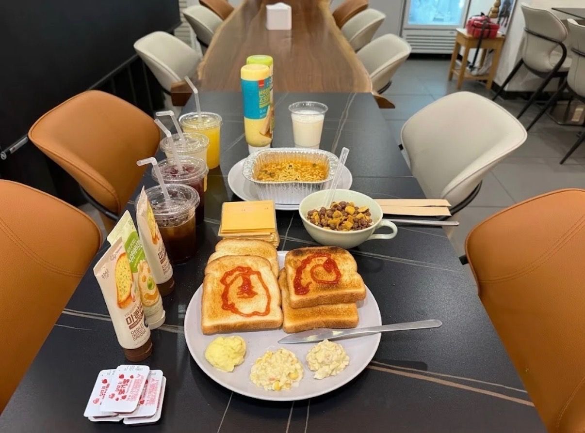 Una mesa de comedor con alimentos, incluyendo tostadas con kétchup, huevos revueltos y un tazón de cereal.