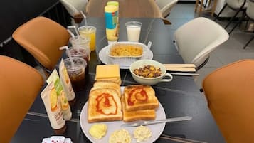 Una mesa de comedor con alimentos, incluyendo tostadas con kétchup, huevos revueltos y un tazón de cereal.