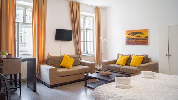 Une chambre d’hôtel avec deux canapés, un lit, un bureau, une télévision et un tableau au mur.