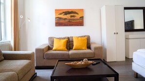 Un salon comprenant un canapé, une table basse avec un saladier, un tableau, un meuble et un téléviseur.