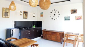 A modern kitchen with a refrigerator, stove, and wooden dining table. - Ramaya House (Tegallalang)