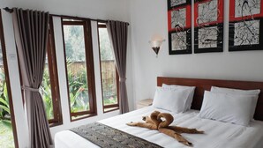 A bedroom with a bed, curtains, a wall-mounted light, and a view of greenery outside. - Ramaya House (Tegallalang)