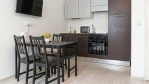 Una cocina moderna con una mesa de comedor, sillas, un televisor de pantalla plana, armarios, un microondas y un horno.