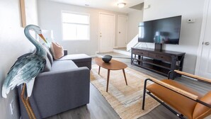 A modern living room with a grey sofa, a wooden coffee table, and a television on a dark wooden stand. - beach. Ocean view. Townhouse (Norfolk)