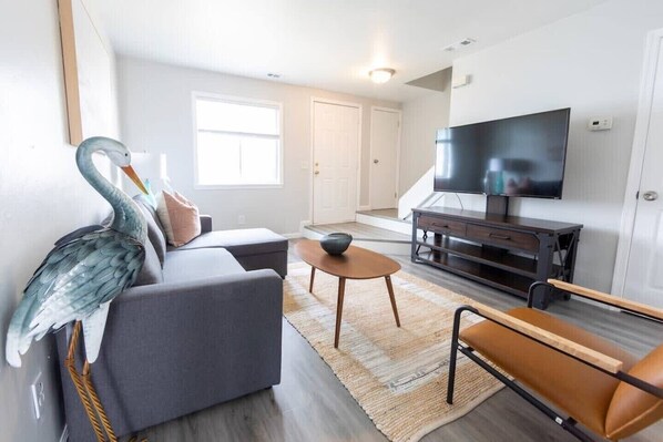 En moderne stue med en grå sofa, et træ sofabord og et fjernsyn på et mørkt træ møbel.