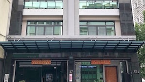 A modern building with a central vertical feature, multiple windows, and a covered entrance area with potted plants. - Meet 57 Homestay (Zhuqi)