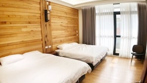 A hotel room with two beds, wooden panel walls, a large window with curtains, and a chair. - Meet 57 Homestay (Zhuqi)