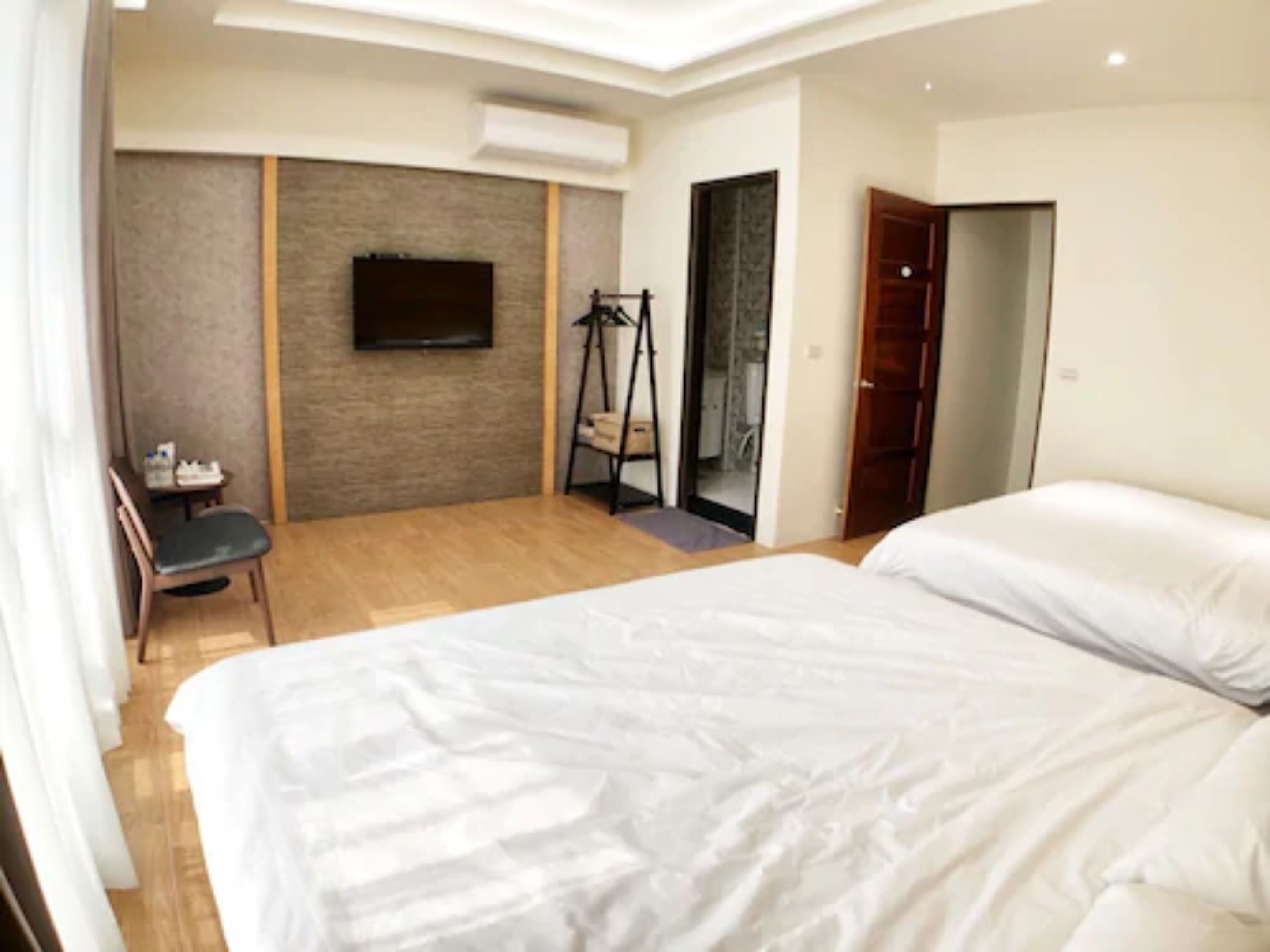 A hotel room with a bed, a chair, a TV, and a wardrobe.