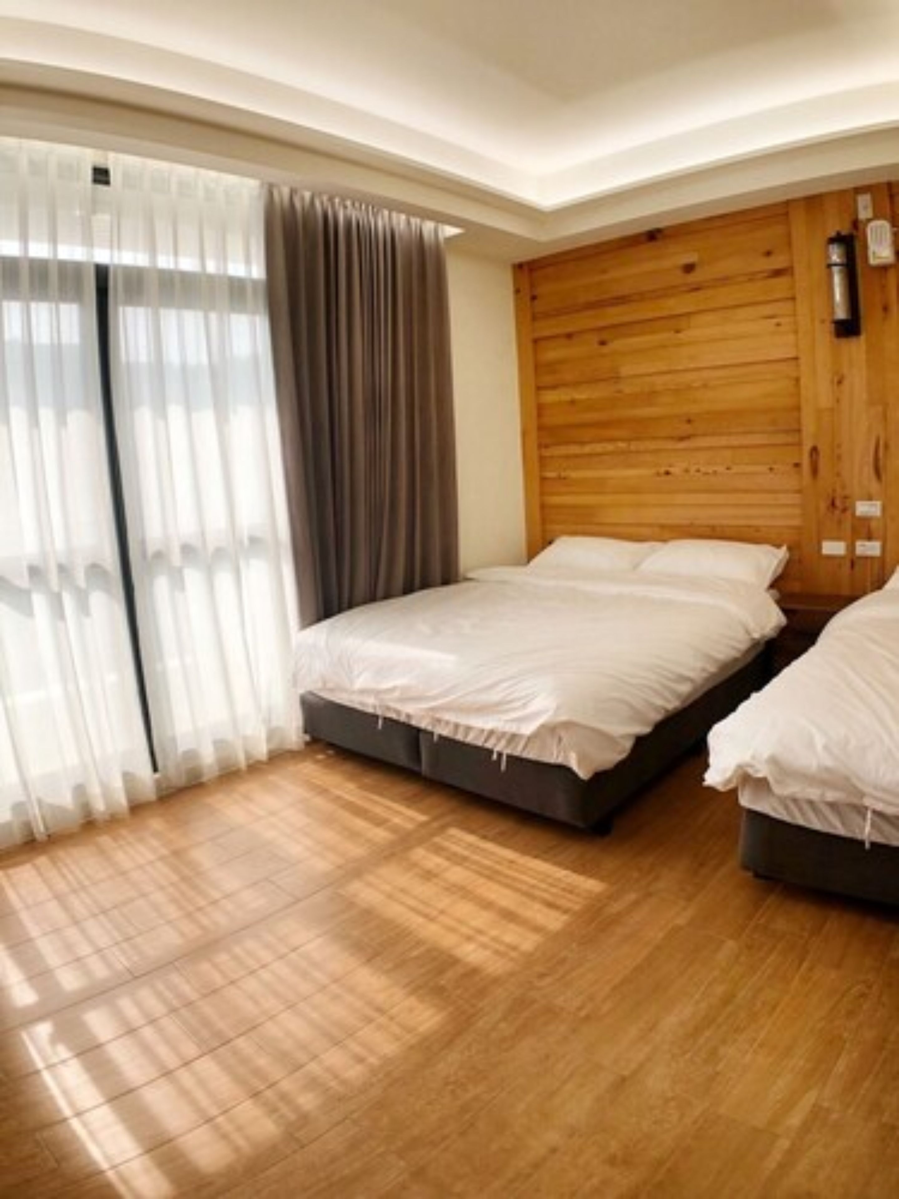 A bedroom with two beds, wooden flooring, and a wooden headboard.