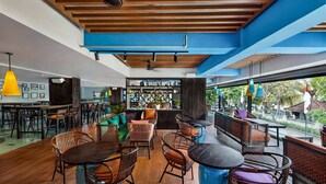Un espacio interior moderno con suelos de madera, una zona de bar y diferentes disposiciones de asientos.