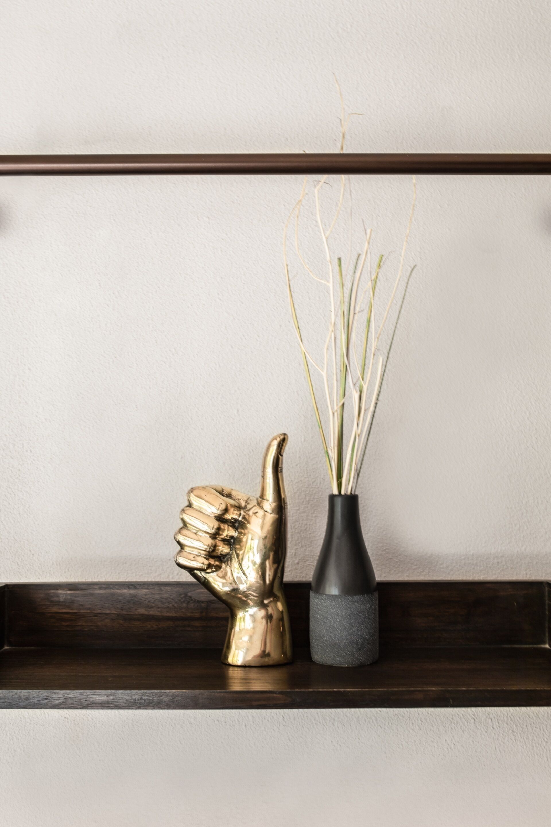 A shelf with a golden sculpture and a vase with dried plants.