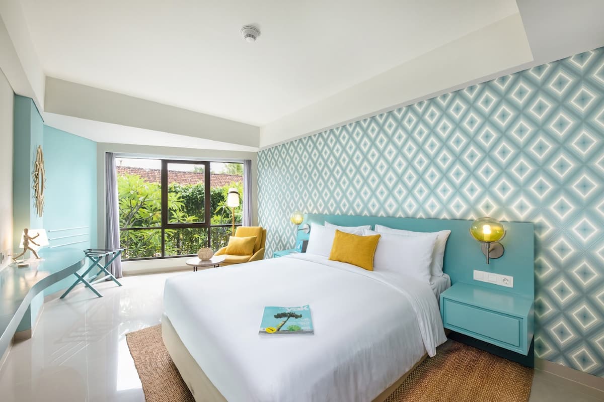 Een moderne slaapkamer met een groot bed, nachtkastje, stoel en uitzicht op groen.
