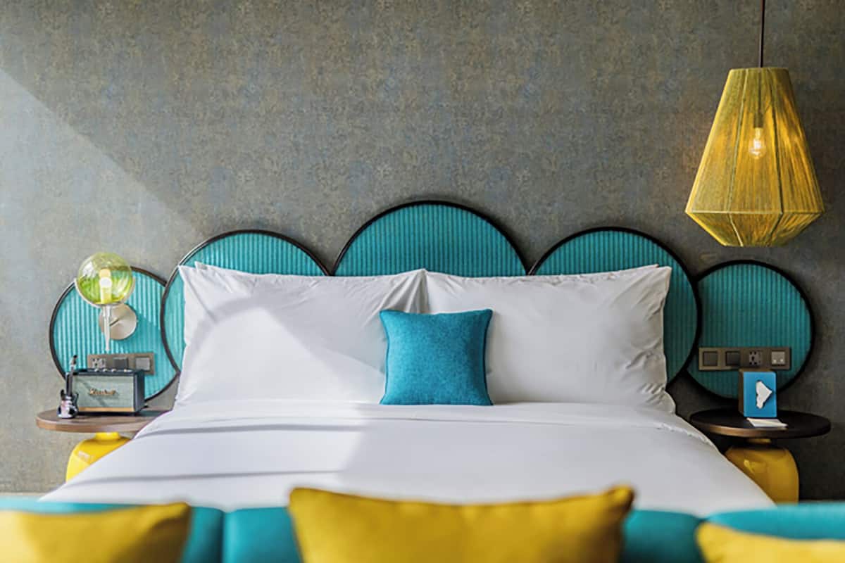 Een moderne slaapkamer met een bed, nachtkastje, lamp en een wandklok.