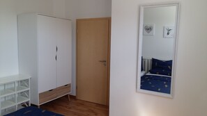 Een slaapkamer met een kledingkast, een deur en een bed met een blauw deken.