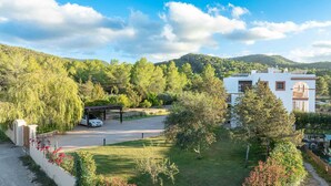 A modern villa with a covered carport, a well-maintained lawn, and a view of the surrounding hills. - CASA FENIX (Sant Josep de Sa Talaia / San Jose)