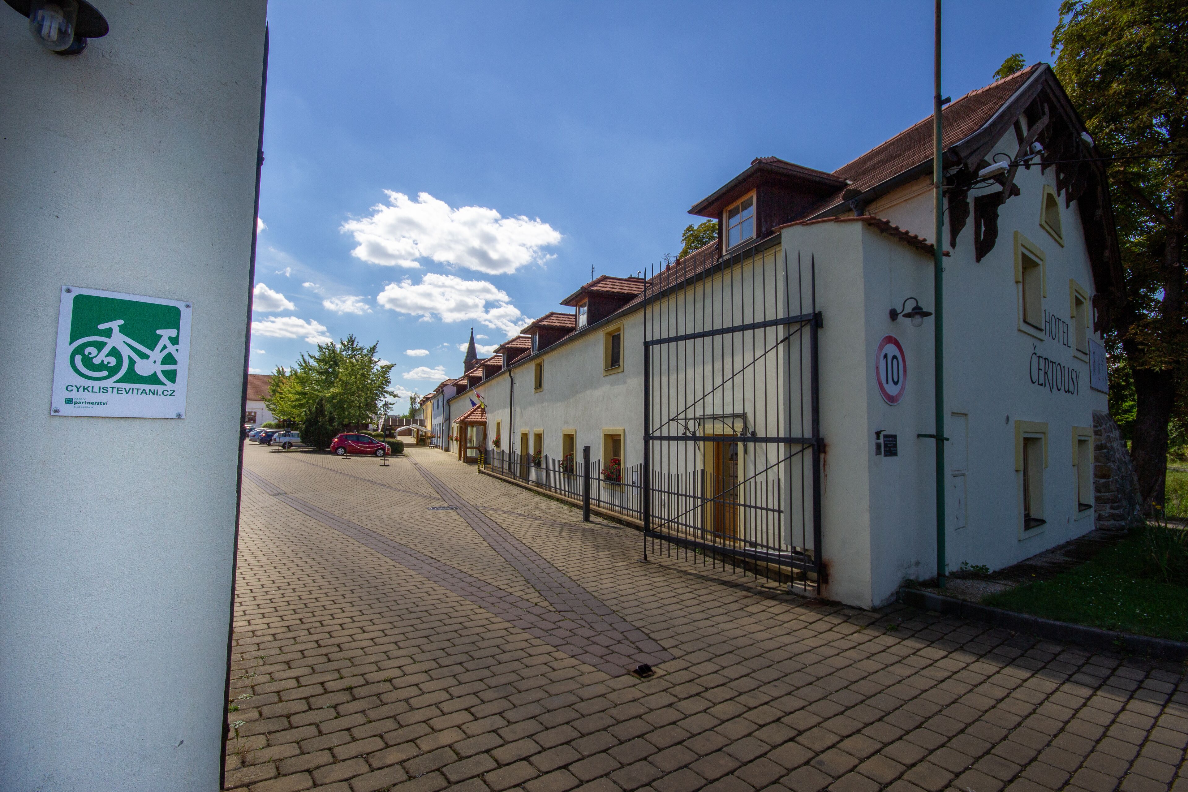 A cobblestone street with a white building featuring a sign for 'Hotel Certouš'.