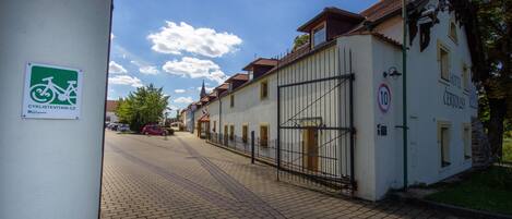A cobblestone street with a white building featuring a sign for 'Hotel Certouš'.