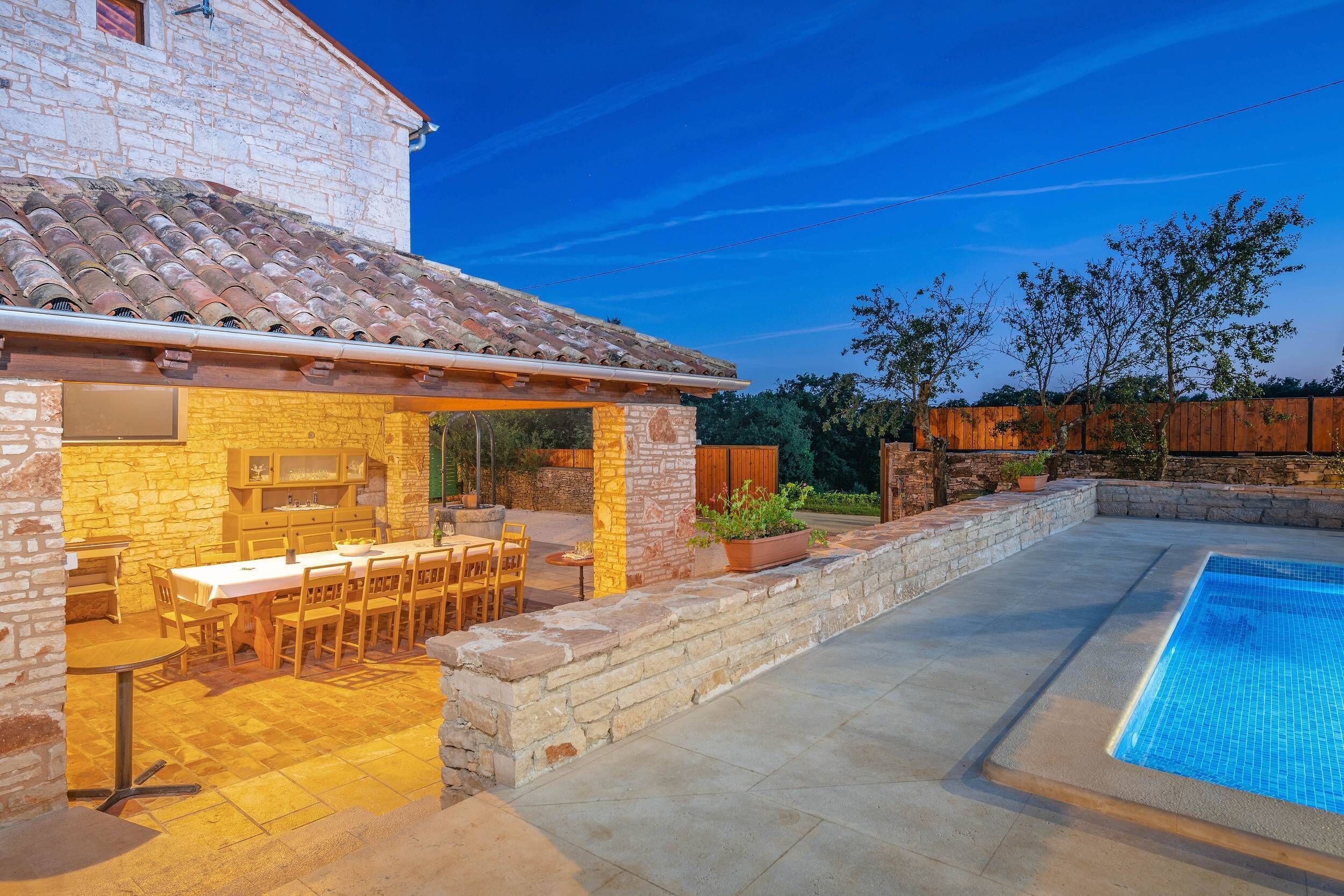 En bygning i sten med tegltag, pool og udendørs møbler.