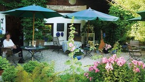 An outdoor patio with tables and chairs, surrounded by potted plants and flowers. - Grashöfle (Sankt Oswald-Riedlhuette)