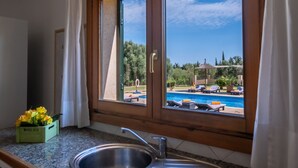 A kitchen with a large window overlooking a pool area. - Vela 1 Finca for 8 with pool in Playas de Muro (Muro)