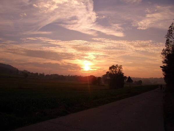 Un atardecer sobre un paisaje rural con campos y una carretera.