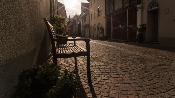 A cobblestone street with a bench and buildings. - Schlafplätzle (Karlstadt)