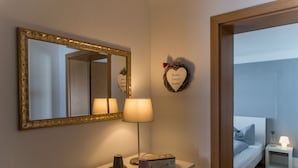A bedroom with a bed, bedside table, lamp, mirror, and a decorative heart-shaped sign on the wall. - Schlafplätzle (Karlstadt)