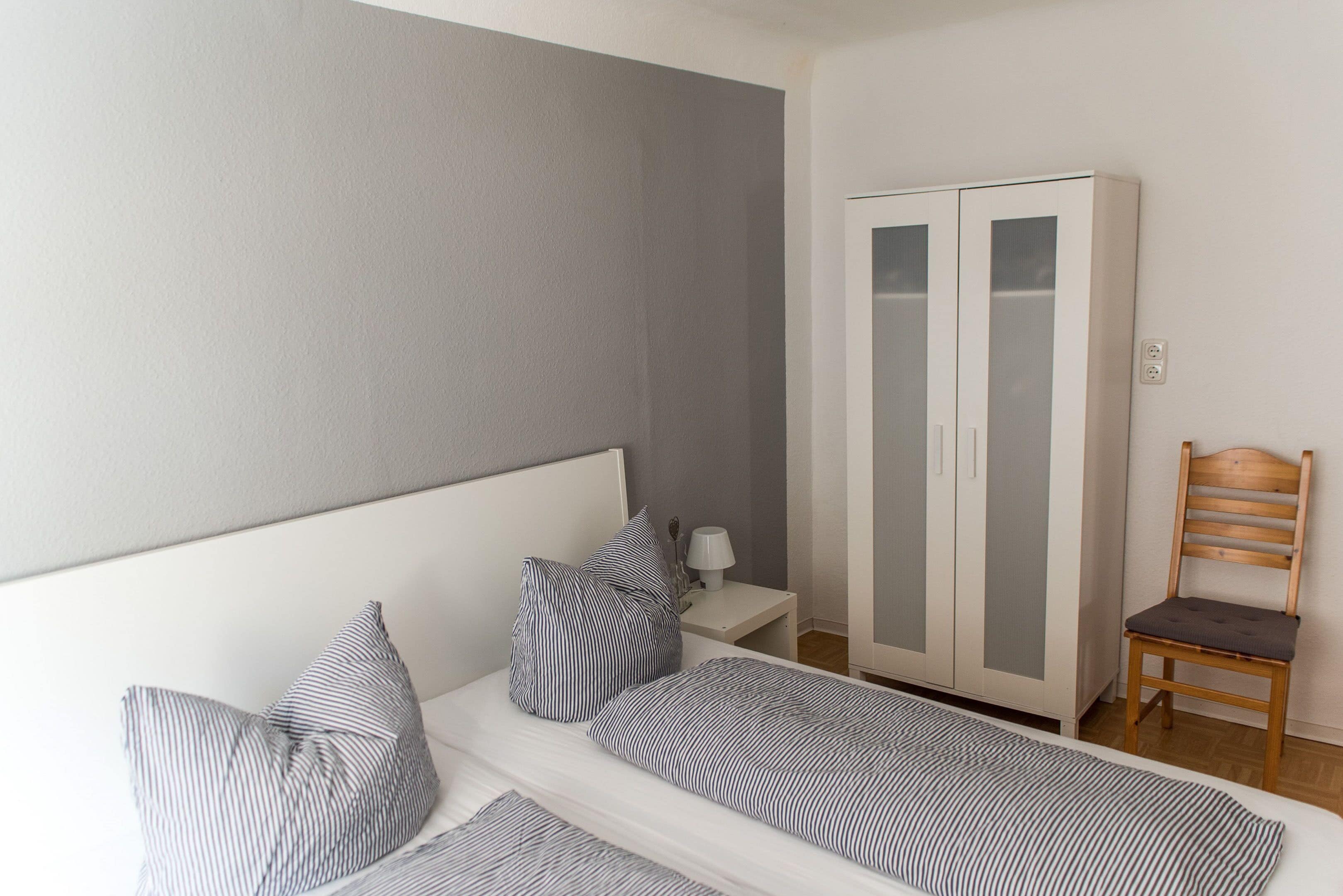 Ein Schlafzimmer mit Bett, Nachttisch, Kleiderschrank und Stuhl.