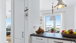 A modern kitchen with white cabinets, a black countertop, and a hanging light fixture. - Himmel & Meer - Terrace, Grill, Fireplace, Washing Machine, Underfloor Heating (Olpenitz)