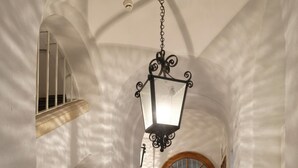 A hallway with a wooden door at the end, a hanging lantern, and a staircase with a railing. - Extremely central 2 BR Apartment next to St  Stephen Cathedral (Vienna)