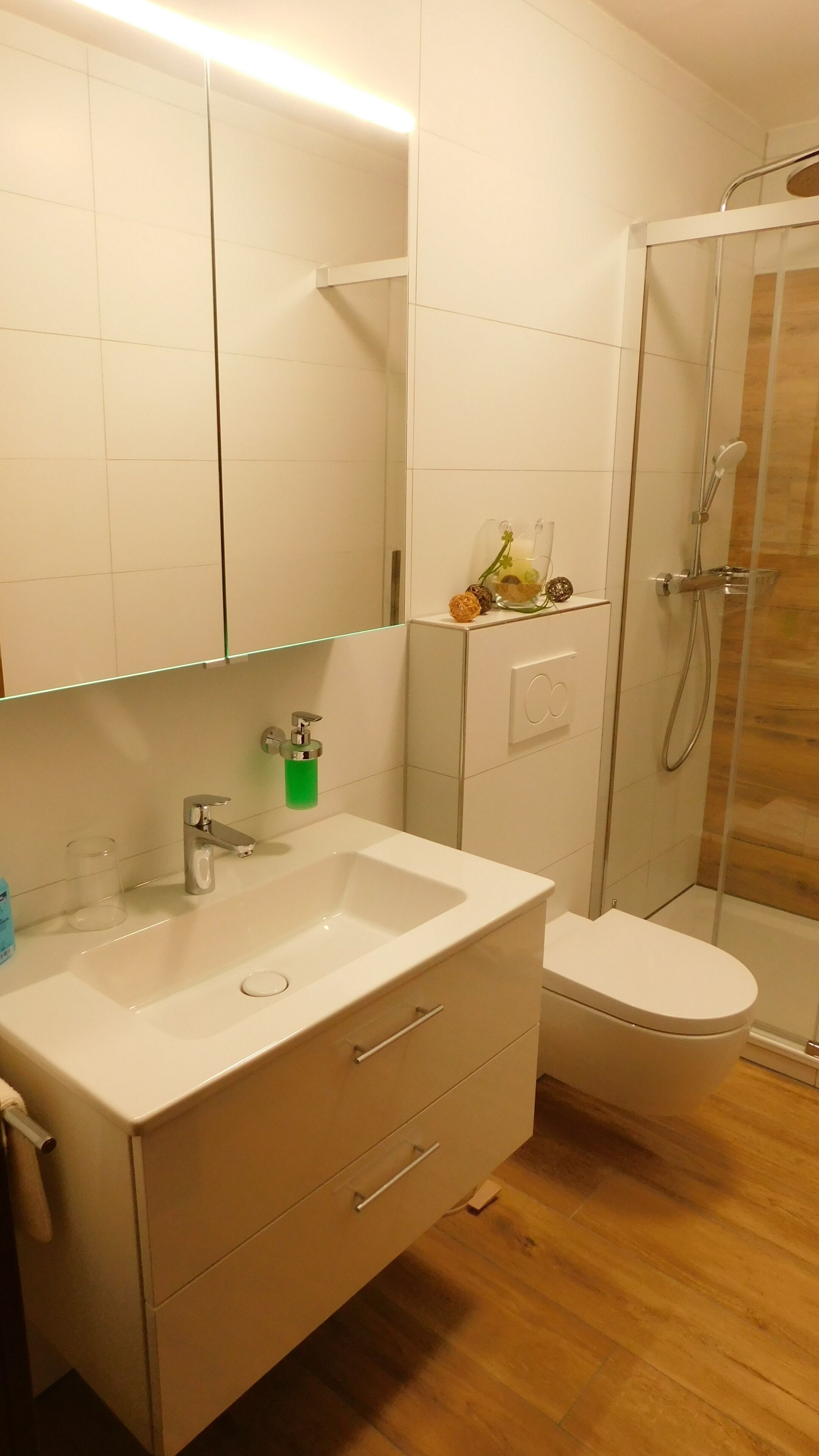 A modern bathroom with a white vanity, a glass shower enclosure, and a toilet.