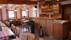 A restaurant with wooden furniture, a bar area, and a large potted plant.