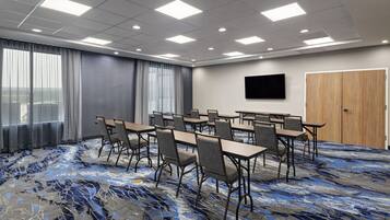 A conference room with a large window, a flat-screen TV, and a patterned carpet.