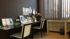 A reception desk with brochures, a vase with flowers, and a window with blinds. - Hotel Aisis Kakegawa (Kakegawa)