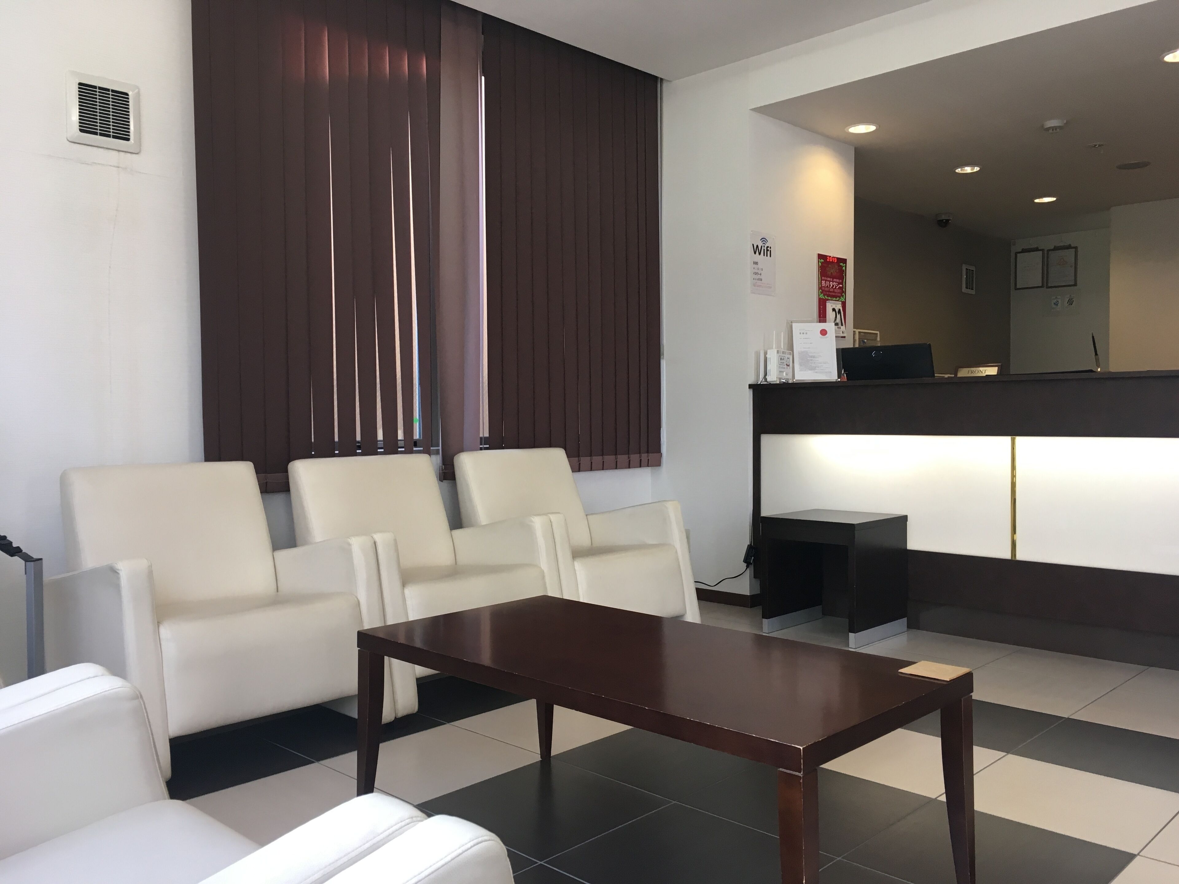 Un hall d’hôtel comprenant un comptoir d’accueil, un espace d’attente avec quatre chaises et une table basse.
