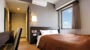 A hotel room with a bed, a desk, a chair, a nightstand, a lamp, and a window with curtains. - Hotel Aisis Kakegawa (Kakegawa)