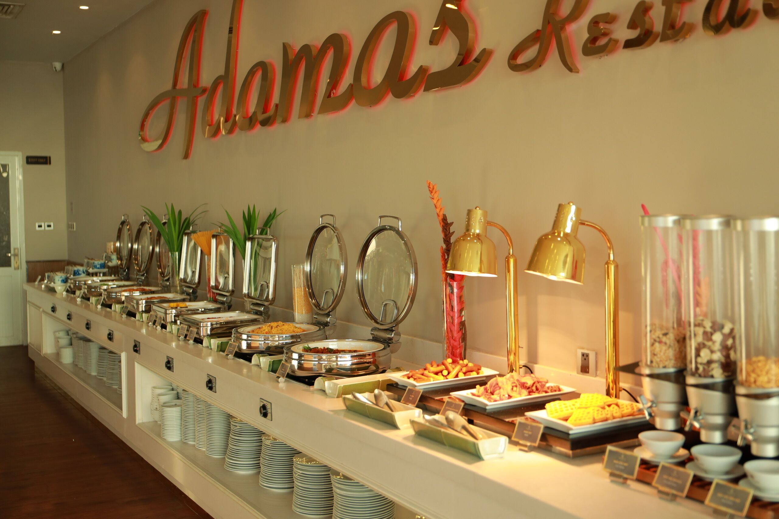 Montaje de bufé con diferentes opciones de comida y un letrero que dice 'Adama's Restaurant'.