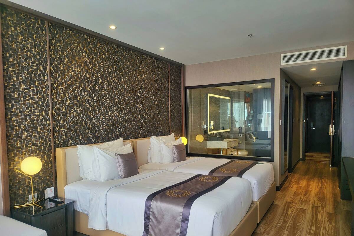 A hotel room with a large bed, a bedside table, a mirror, and a view of the bathroom.