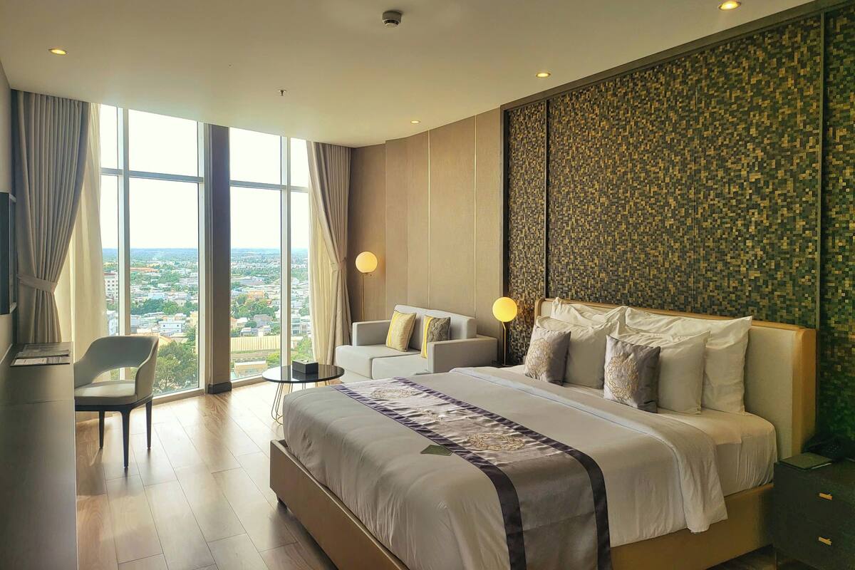 A modern hotel room with a large bed, a desk, and a chair.