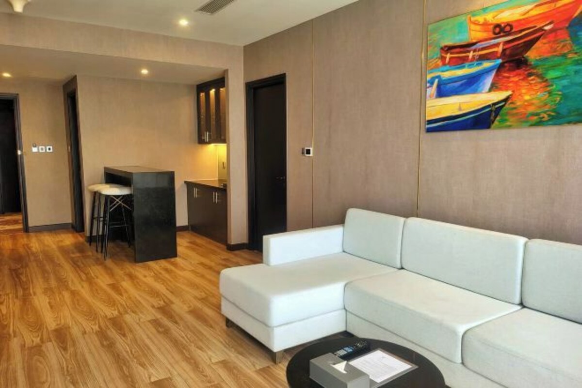 Uma sala de estar moderna com um sofá, uma mesa pequena e uma pintura na parede.