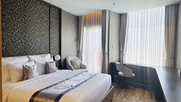 Een moderne hotelkamer met een groot bed, een bureau en een uitzicht op de stad door grote ramen.
