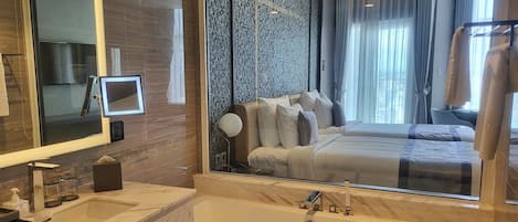 Un baño de hotel moderno con un espejo grande, una bañera y un lavabo.