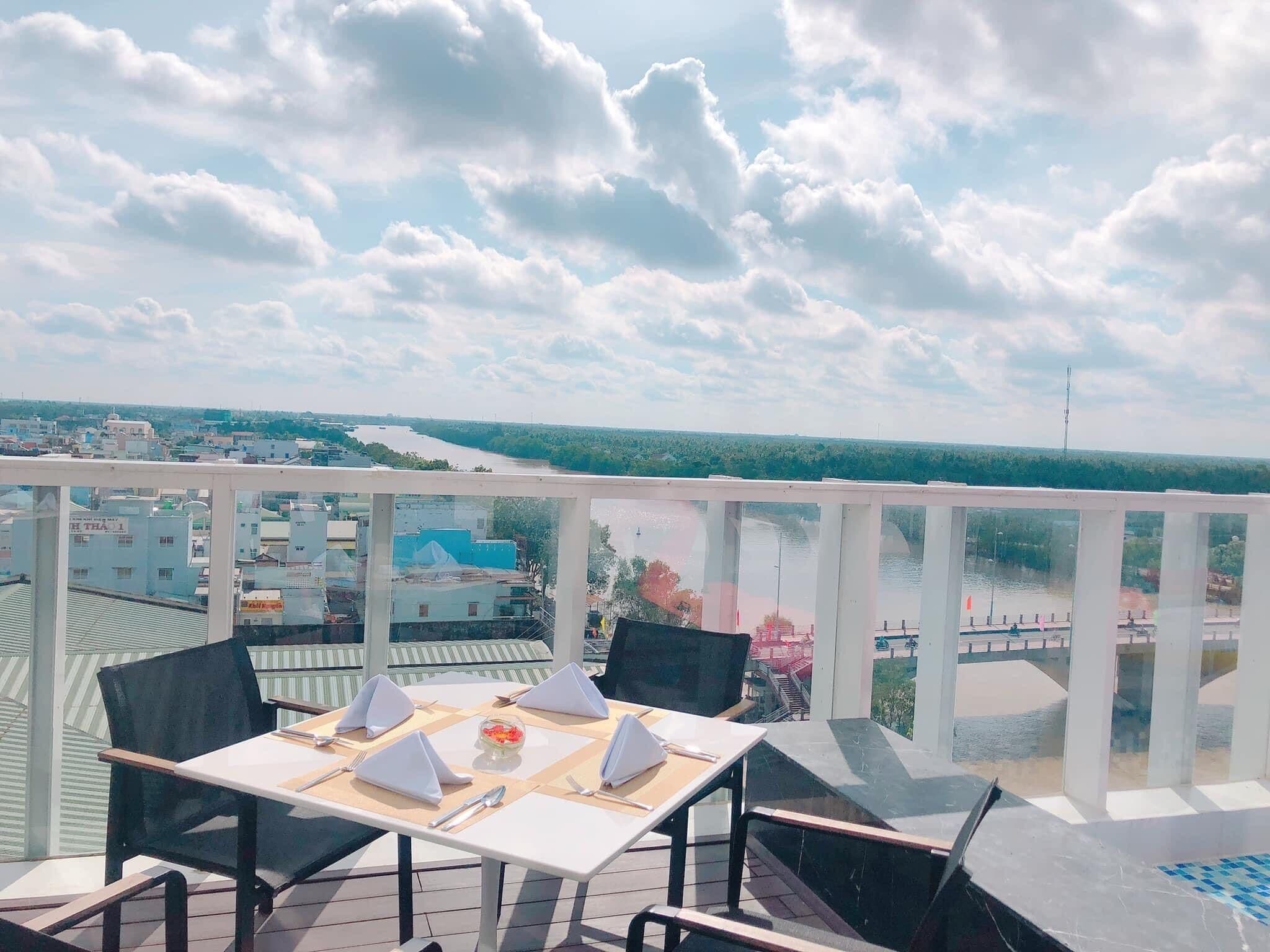 A table set for four with a view of a river and buildings in the distance.