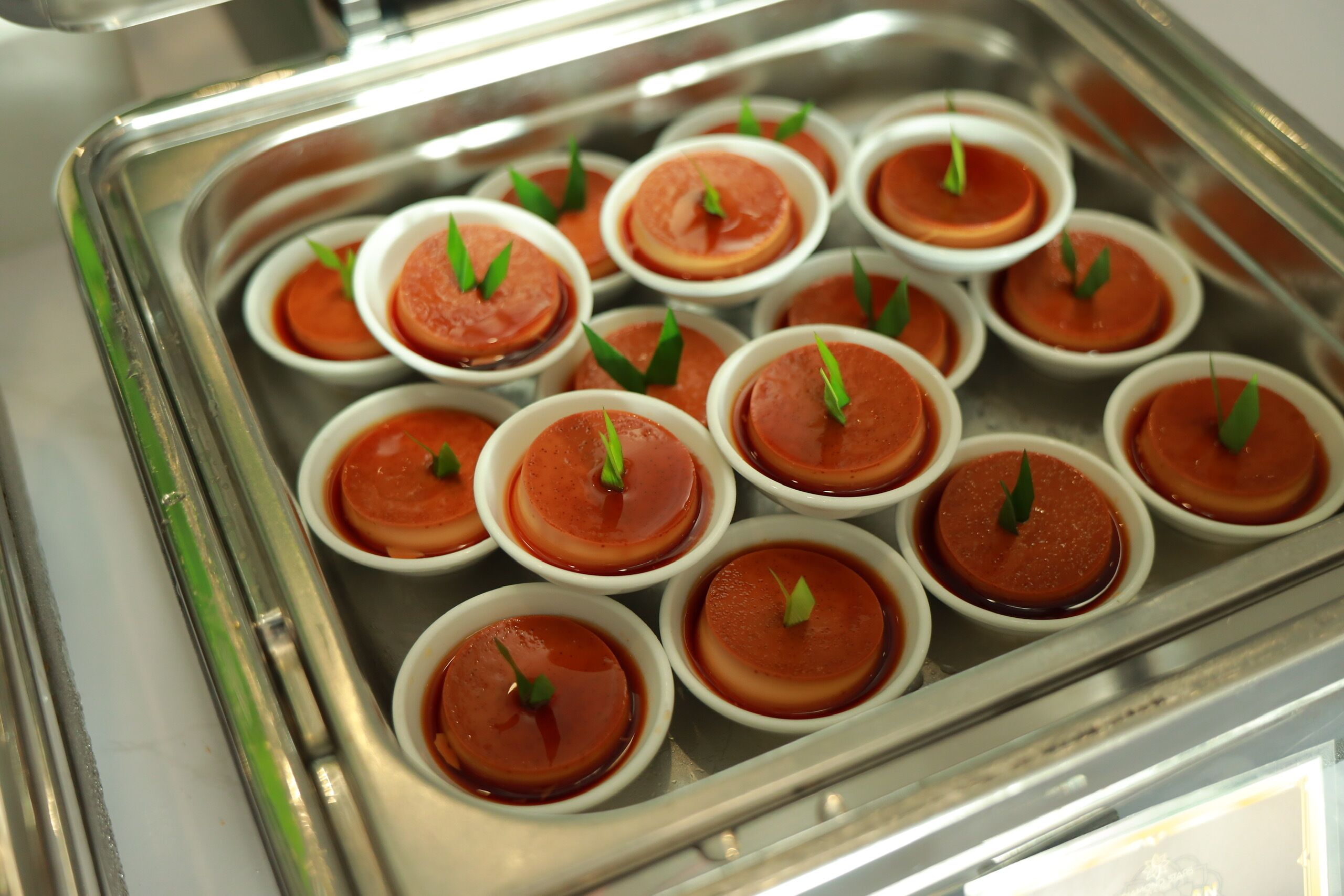 Een schaal met kleine dessertbekertjes, rood saus en garnering.