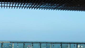 An infinity pool with clear blue water, metal pool ladders, and a view of a cityscape through a glass railing.