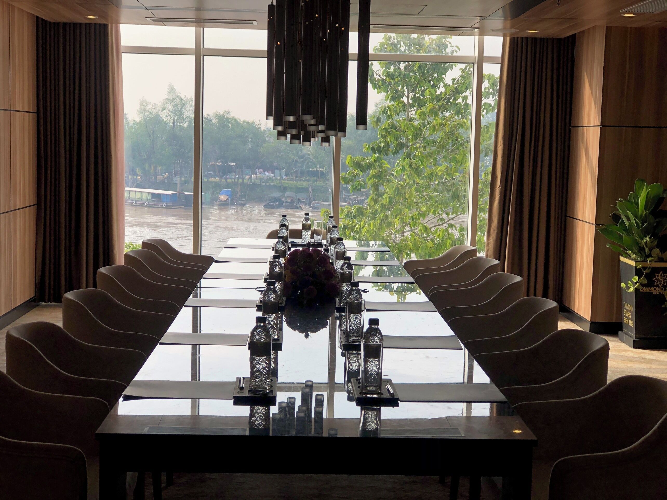 Sala de conferências com uma mesa comprida, cadeiras e vista para um rio.