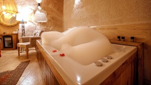 Un cuarto de spa con una bañera grande, piso de madera y un espejo con marco decorativo.