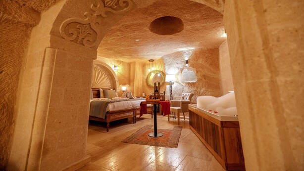 Un dormitorio acogedor y bien iluminado, con una cama grande, una sala de estar con mesa y sillas, y una bañera.