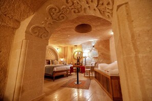 A cozy, well-lit bedroom with a large bed, a sitting area with a table and chairs, and a bathtub. - Misty Cave Hotel (Ürgüp)