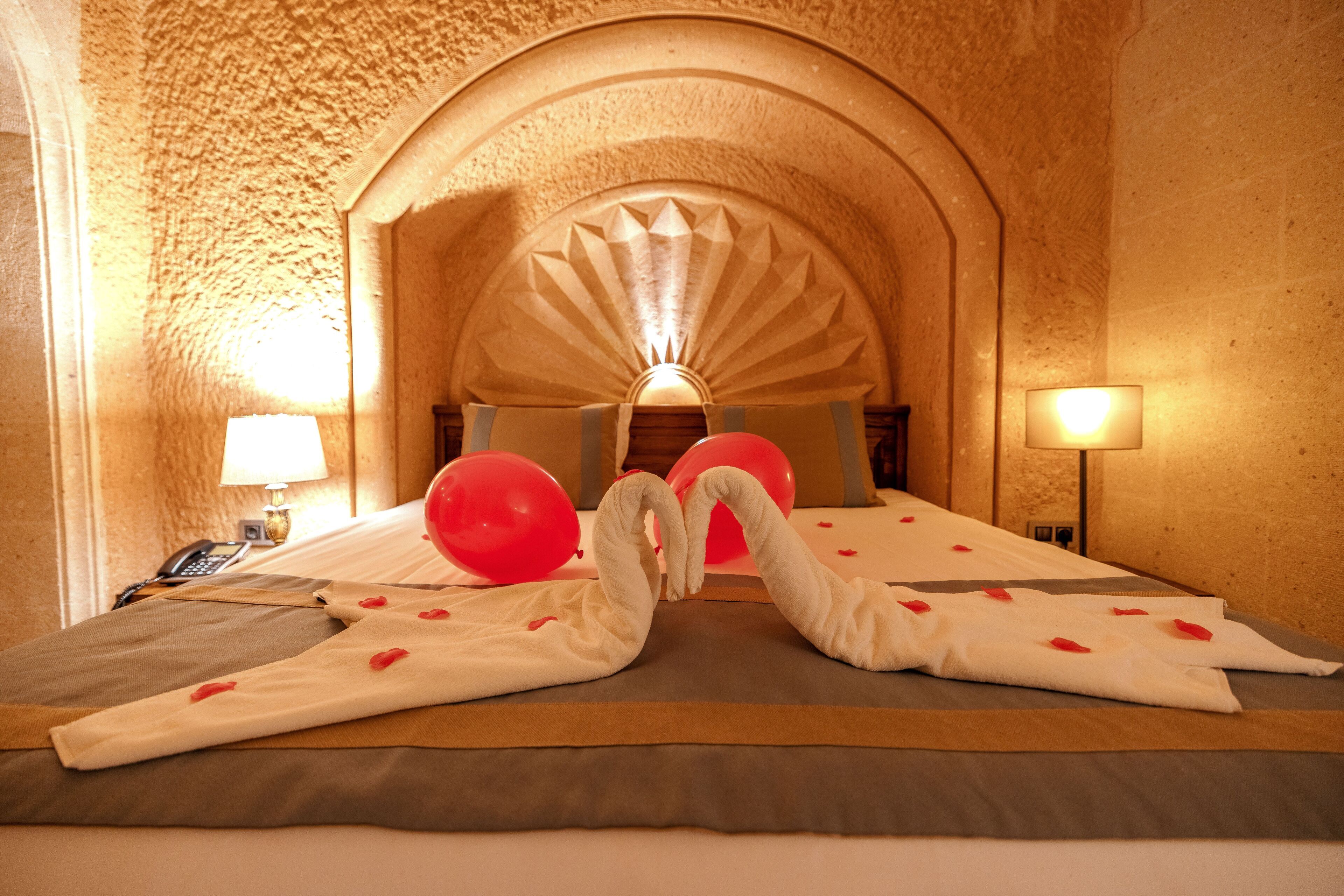 A hotel room with a bed, pillows, a lamp, and a telephone.